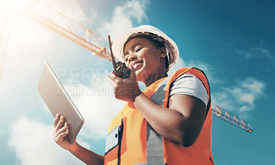 Buy stock photo Shot of a young woman using a digital tablet and walkie talkie while working at a construction site