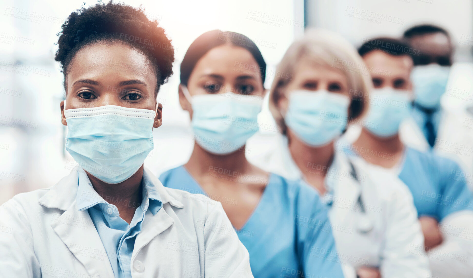 Buy stock photo Portrait of a group of medical practitioners wearing face masks while standing together in a hospital