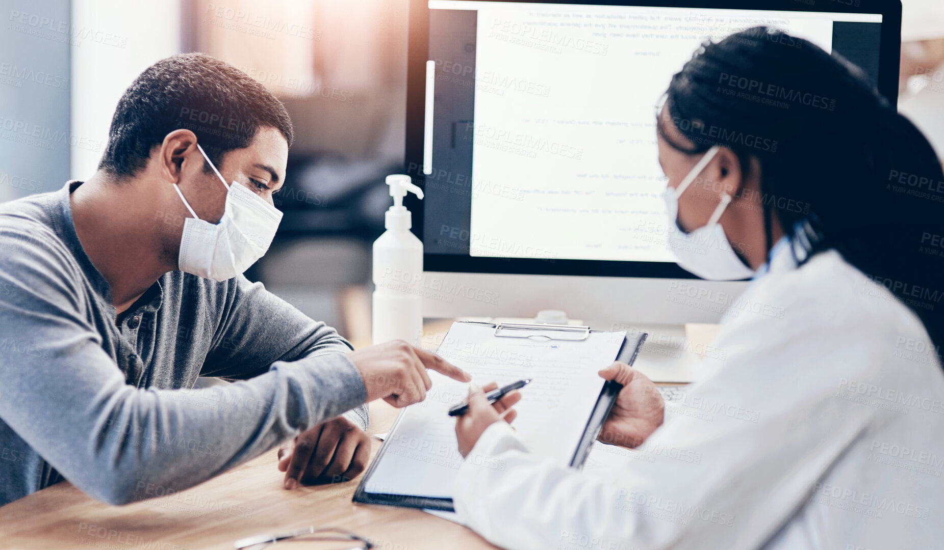 Buy stock photo Shot of a young man going through paperwork during a consultation with a doctor