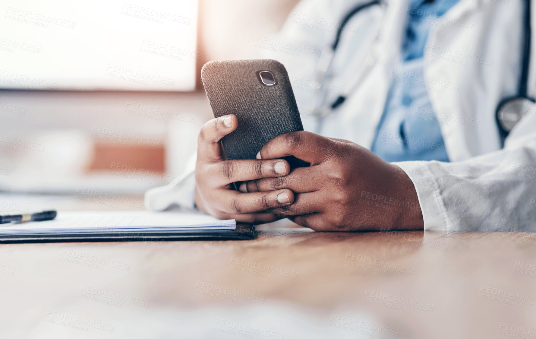 Buy stock photo Closeup shot of an unrecognisable doctor using a cellphone while working in her office