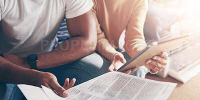 Buy stock photo Shot of a young couple using a digital tablet while going through paperwork together at home