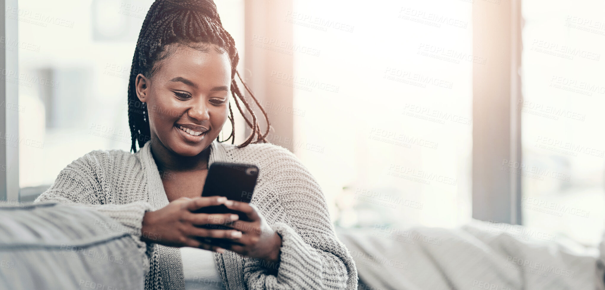 Buy stock photo Shot of a young woman using a smartphone on the sofa at home