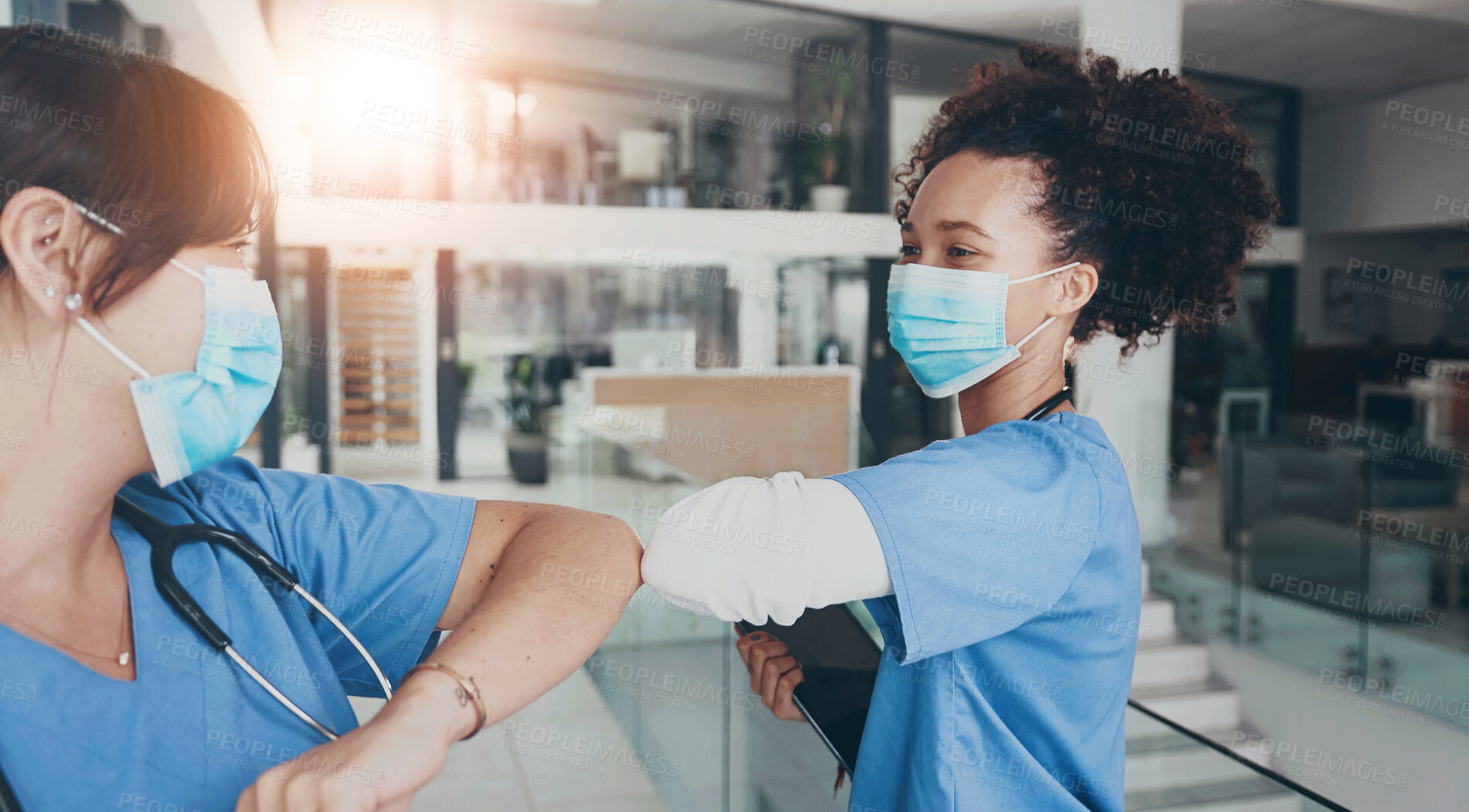 Buy stock photo Cropped shot of an attractive young nurse standing and elbow bumping a coworker as a greeting in the clinic