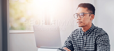 Buy stock photo Shot of a young businessman using a laptop in an office