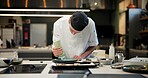 Man, chef and serious with sauce in kitchen at restaurant for fine dining, meal and creativity. Male employee, professional and cooker with food for culinary, hospitality and catering service