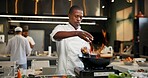 Black man, chef and seasoning with frying pan in kitchen at restaurant for fine dining, meal and creativity. Employee, professional and cooker with food for culinary, hospitality and catering service