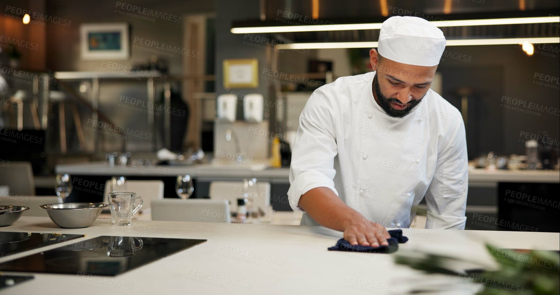 Buy stock photo Man, chef and serious with cleaning kitchen counter at restaurant for fine dining, meal and creativity. Male employee, professional and cooker with cloth for culinary, hospitality and catering