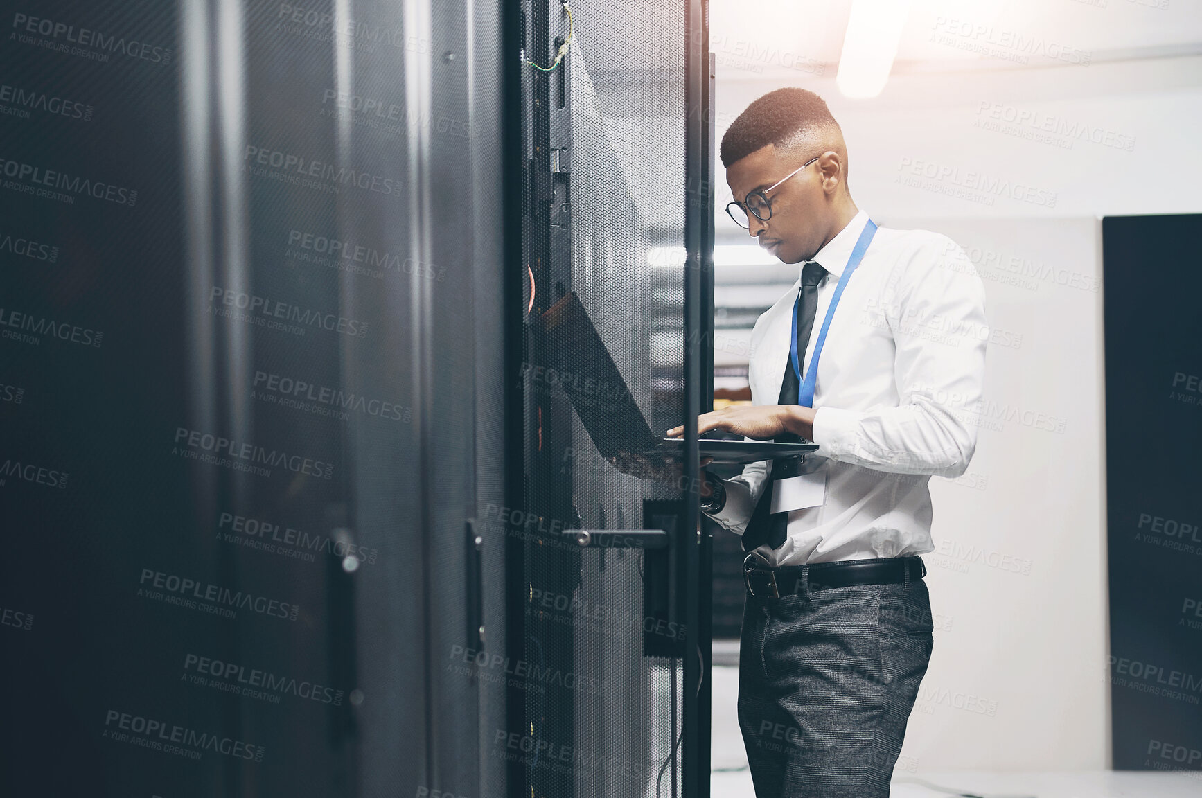 Buy stock photo Shot of a young male IT technician in a server room