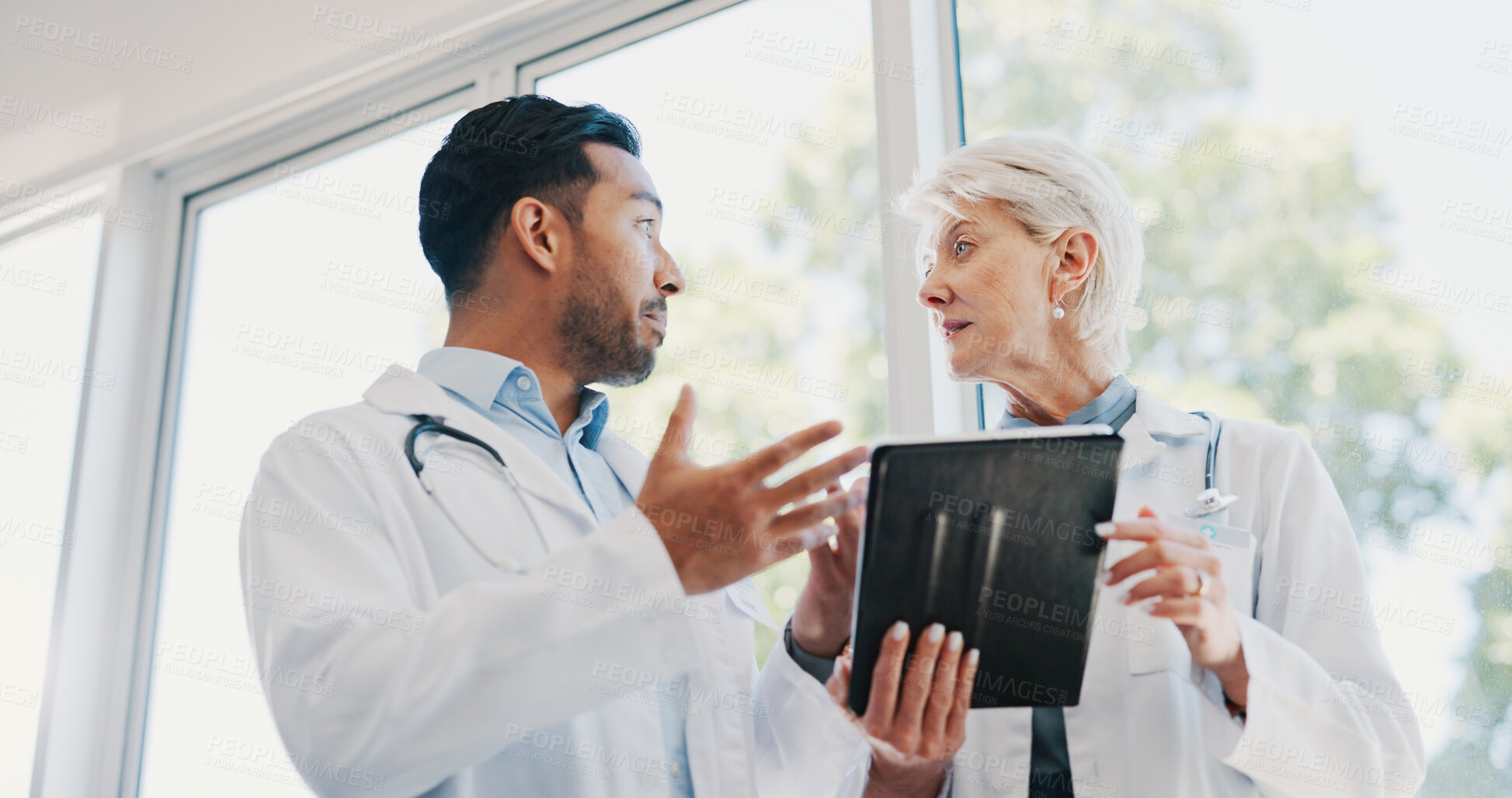 Buy stock photo Hospital, meeting and doctors with tablet in discussion for healthcare research, planning and help. Man, woman and low angle with tech at clinic for diagnosis, solution and review of patient records