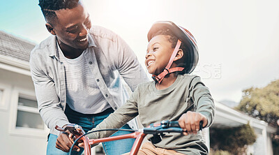 Buy stock photo Shot of a father teaching his son to ride a bicycle outdoors