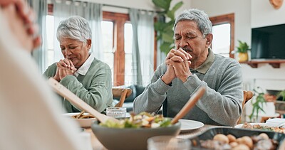 Buy stock photo Senior couple, food and prayer in home with family, blessing and grateful for meal in dining room. Elderly people, faith and eyes closed at table for worship, respect or giving thanks in spirituality