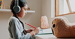 Girl, writing and headphones with homework book for learning, development or listening to music. Child, pencil and notes with audio tech for education, study and scholarship at family house in Mexico