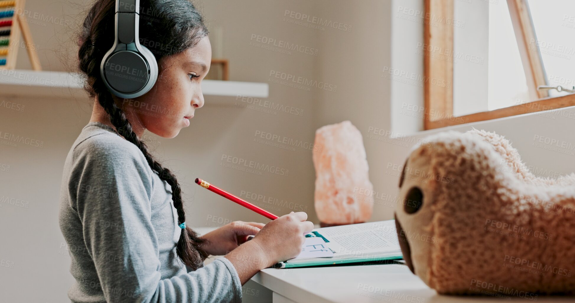 Buy stock photo Girl, writing and headphones with homework book for learning, development or listening to music. Child, pencil and notes with audio tech for education, study and scholarship at family house in Mexico