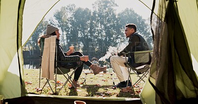 Buy stock photo Camping, couple and relax with coffee in nature by tent with conversation, bonding and wilderness getaway. Man, woman and together with warm beverage outdoor for adventure, back view and peaceful.