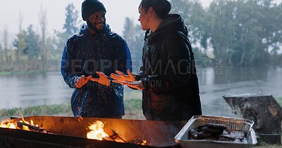 Buy stock photo Couple, hands and fire in outdoor with rain for warm on camp, adventure and winter getaway for holiday. Man, woman and together with bonfire for fireside connection, happiness and lakeside with flame