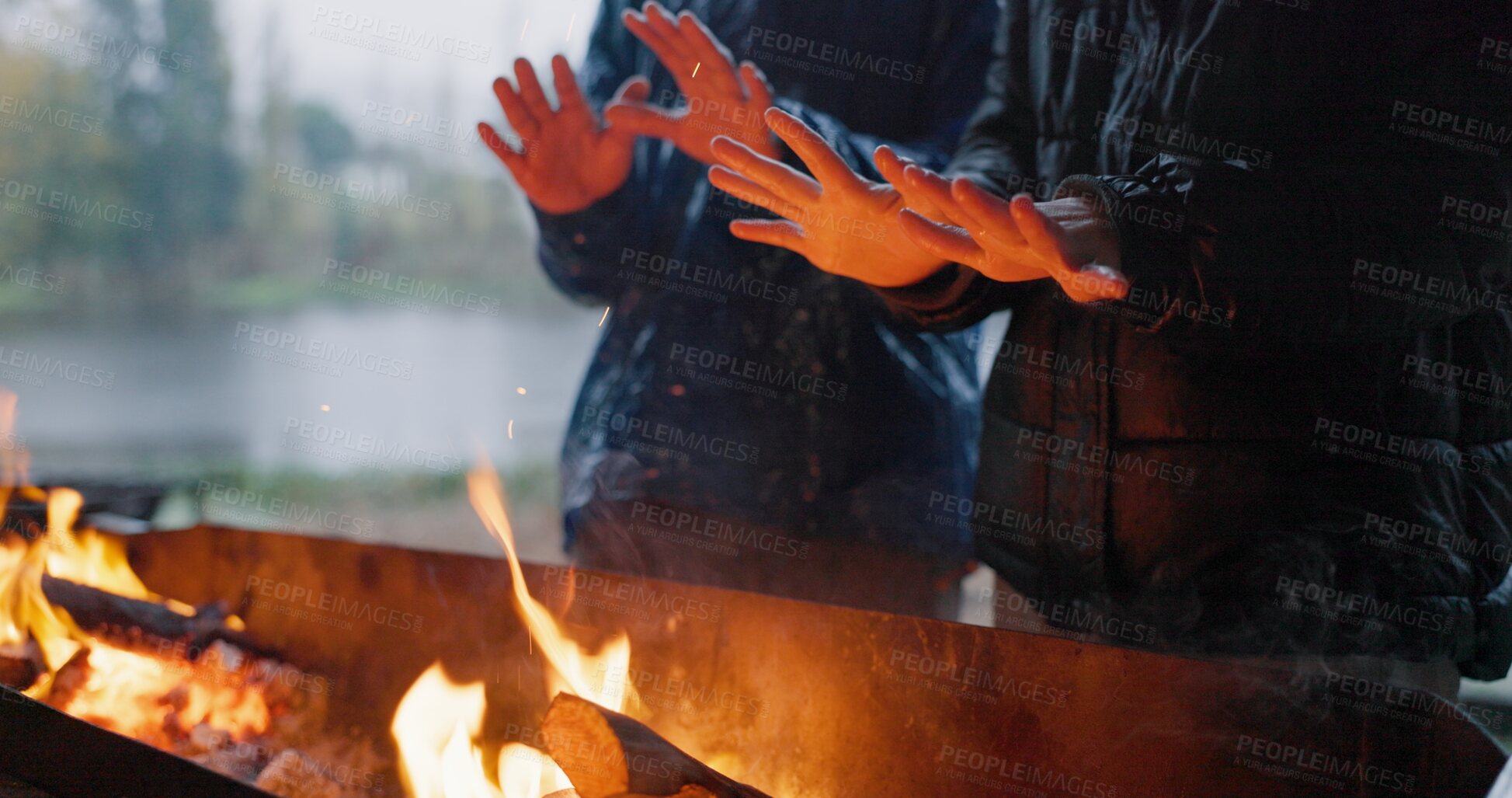 Buy stock photo Friends, hands and fire in outdoor with rain for warm on camp, adventure and winter getaway for holiday. People, together and closeup with bonfire for fireside connection, lakeside and flame.