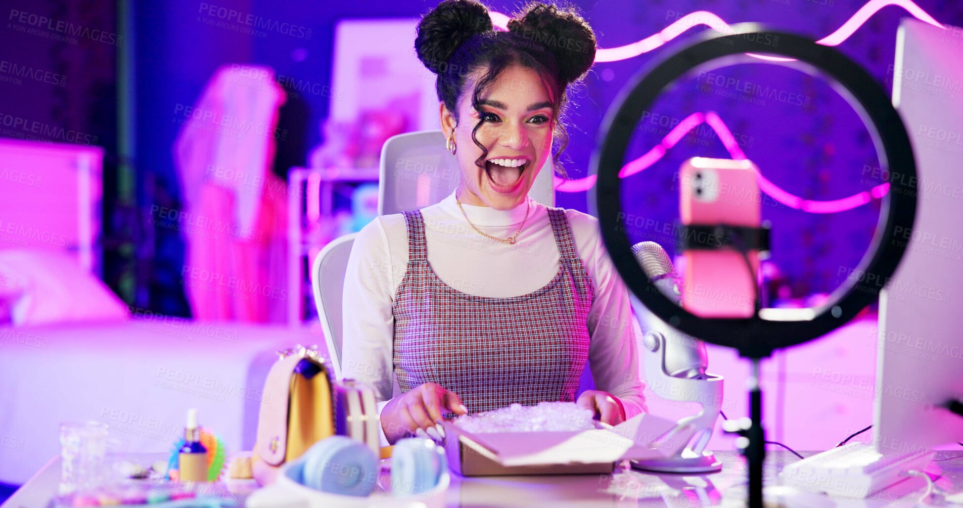 Buy stock photo Unboxing, live stream and happy influencer woman with microphone, neon light and makeup in home studio. Content creator, beauty streamer or excited girl in online video for skincare product review