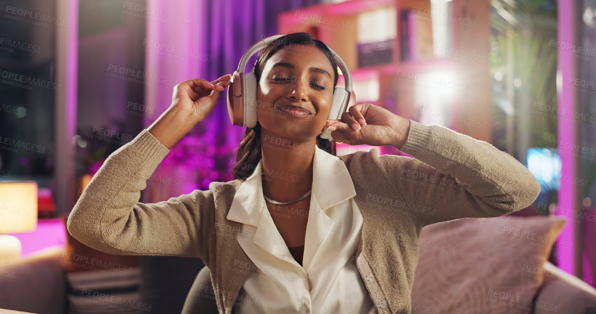 Buy stock photo Headphones, Indian woman and night with dancing, music and home with audio subscription. Neon, streaming and smile with happy, relax and chill track in a living room and listening to pop song on sofa