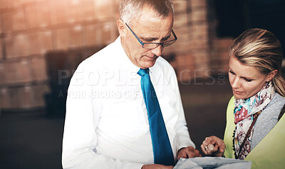 Buy stock photo Two employees discussing a plan while standing in a warehouse.