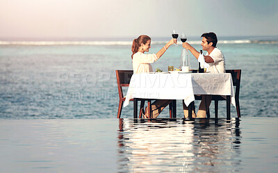 Buy stock photo Romance, couple and cheers to dinner on beach for anniversary date, honeymoon vacation or celebration. Love, people or toast glasses in water of ocean for lunch, bonding and support on luxury holiday