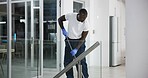 Cleaner, black man and mopping floor in office for fumigation, disinfect and safety suit from disease risk in building. Maintenance, person and chemical liquid of pest control, health and hygiene 