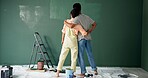 Back, couple and hug with painting wall for house renovations, upgrade and bonding. New home, relationship and people together for fun with support, care and teamwork for love with diy for makeover