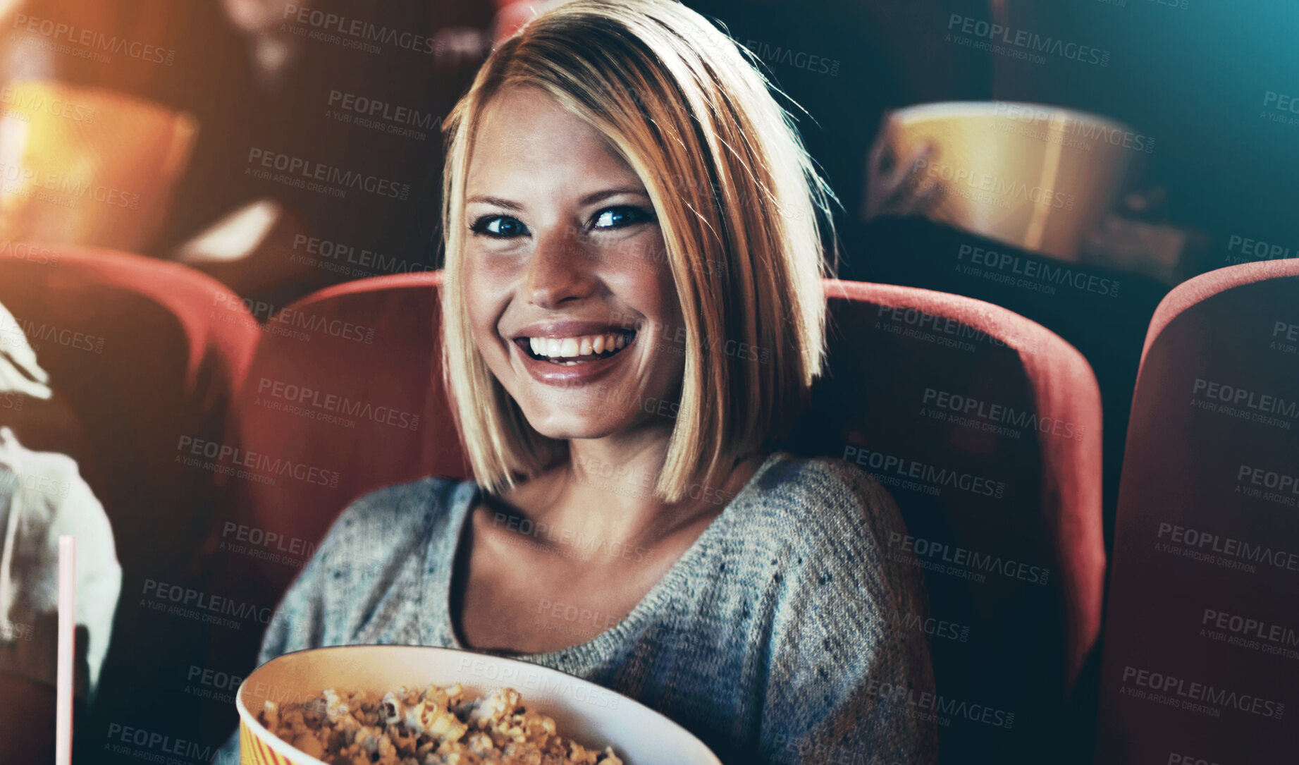 Buy stock photo A portrait of a happy young girl holdng a tub of popcorn and a cold drink in her hands at the movies