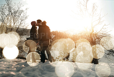 Buy stock photo Two lovers kissing as the sun sets on a snowy landscape