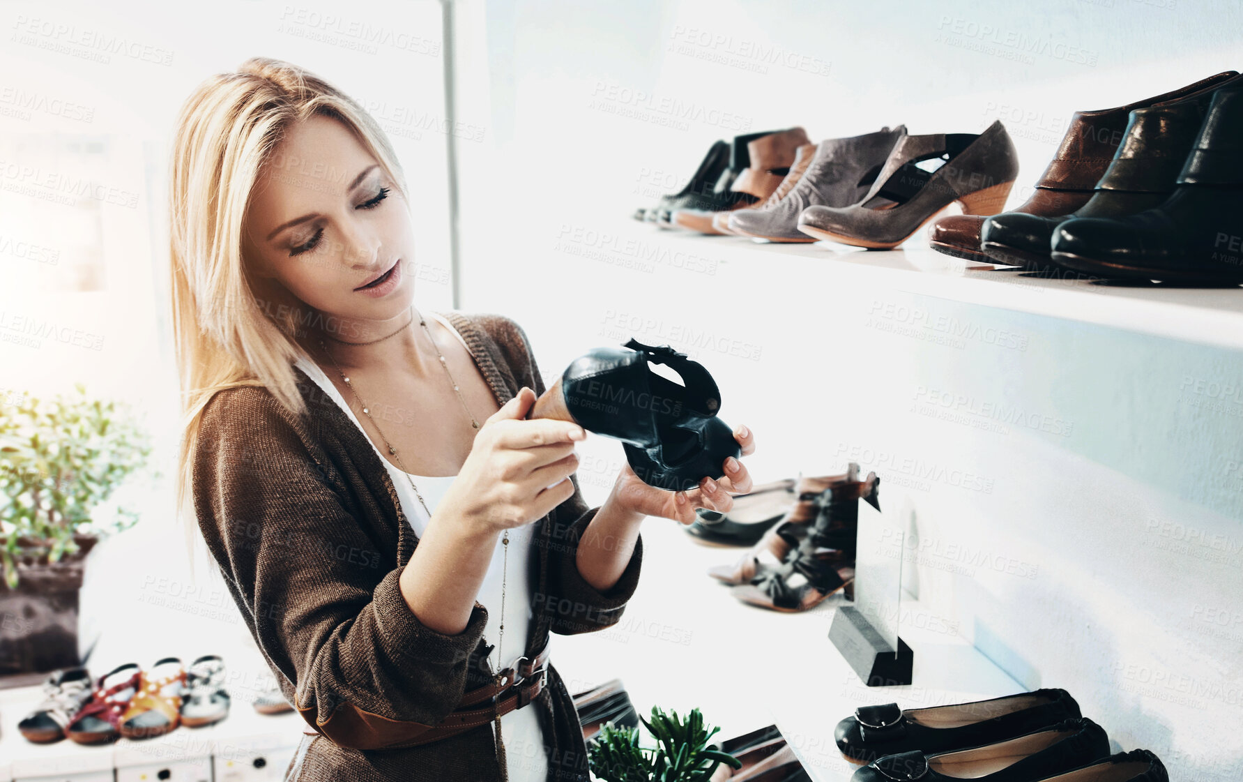 Buy stock photo Pretty young woman looking at the shoe selection at the store