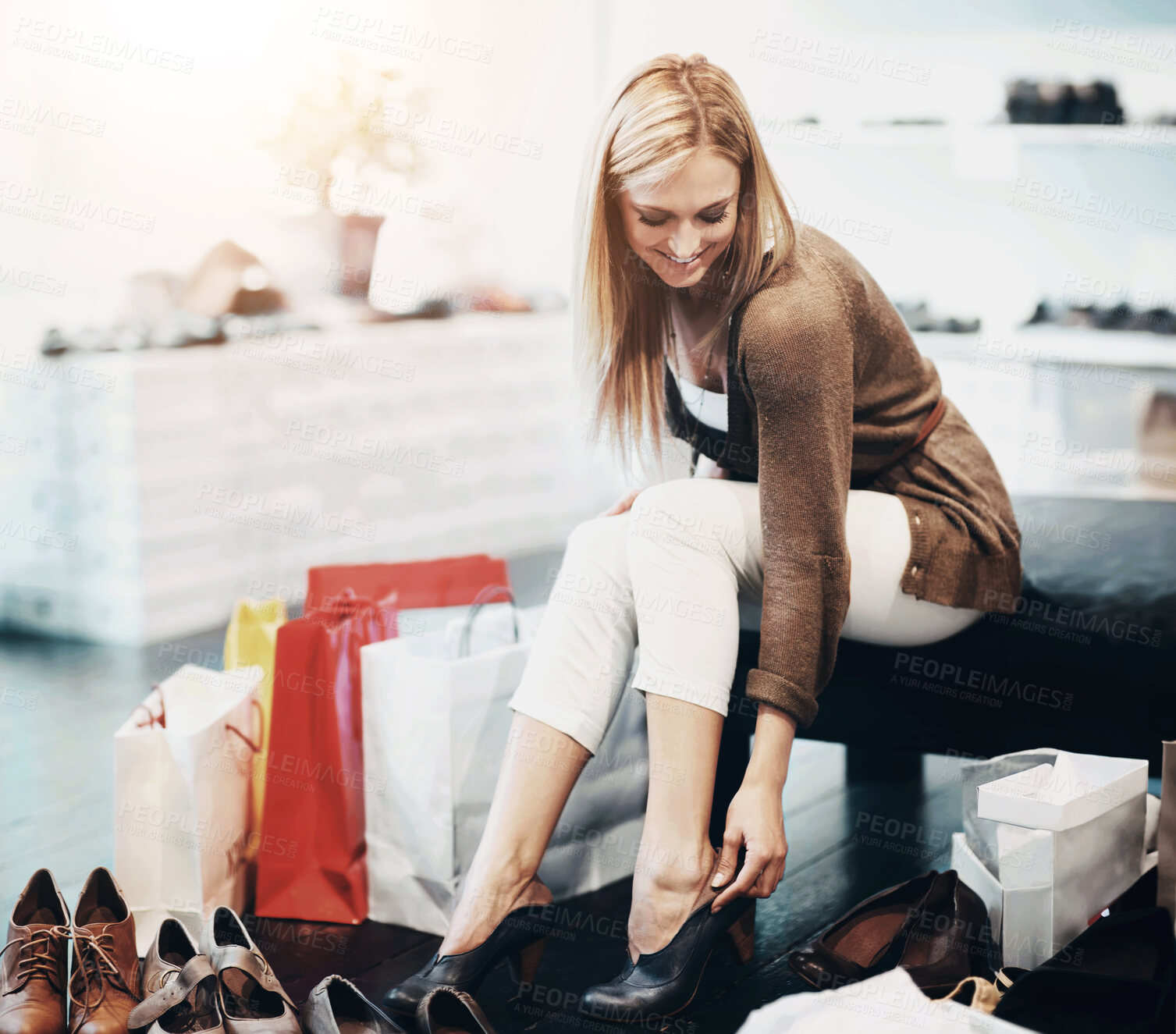 Buy stock photo Shoes, fashion shopping and woman retail customer trying on mall shop stock with a happy smile. Young female feet in heels with outlet bags and happiness in a stylish boutique or trendy shoe store 