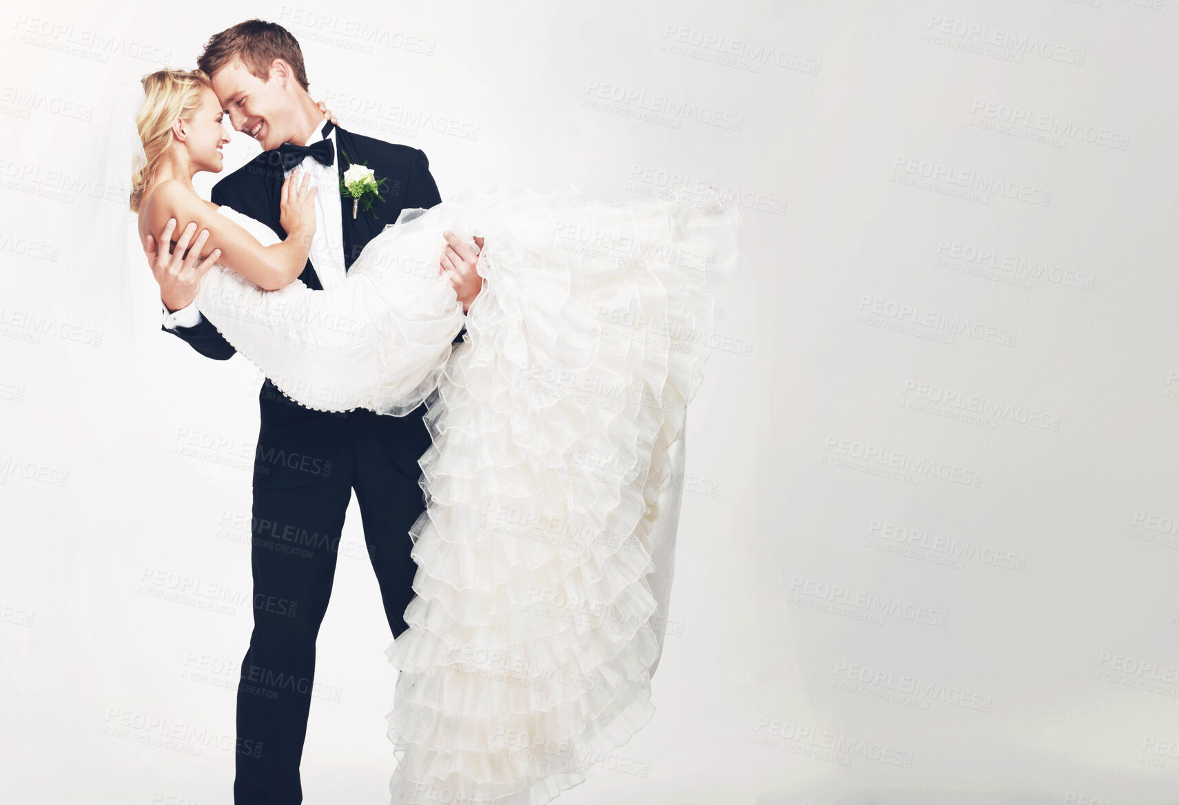 Buy stock photo Attractive young groom holding his bride as they get ready to kiss