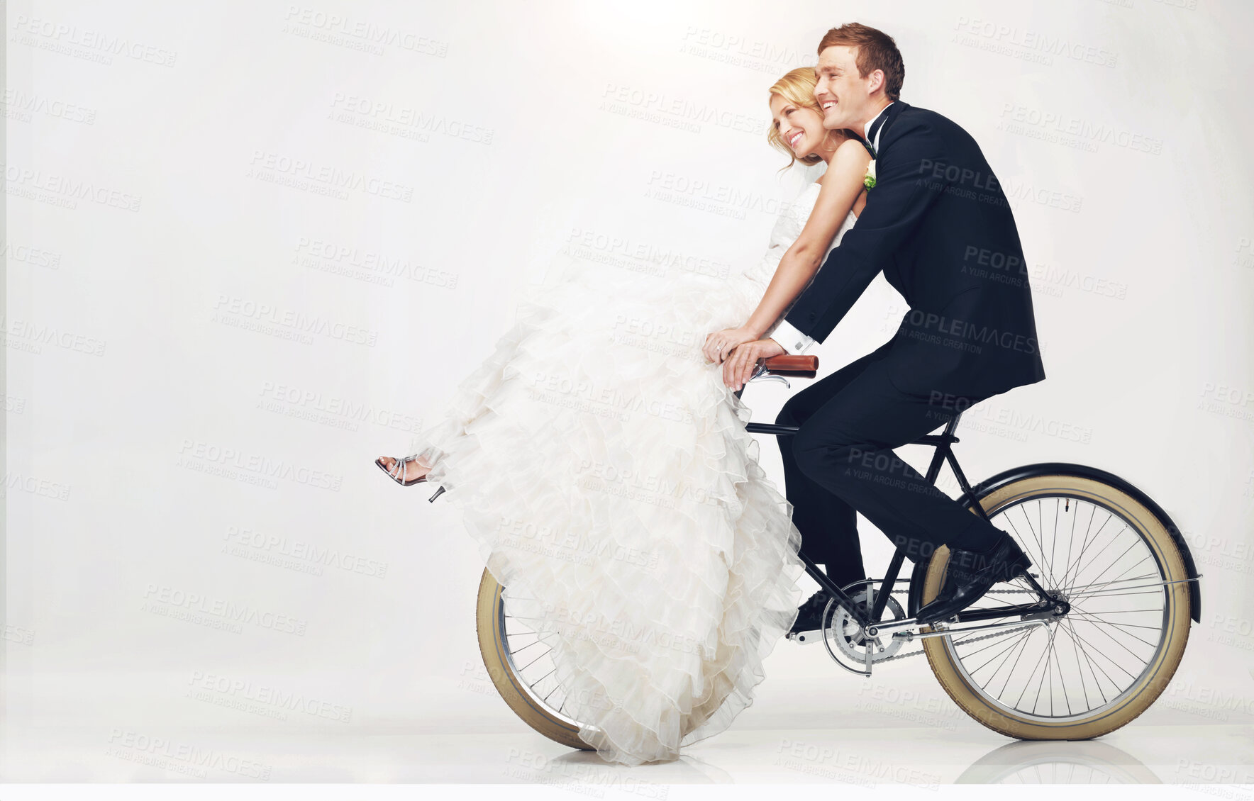 Buy stock photo Happy, wedding and couple on a bicycle against a white background, after getting married together. Love, young bride and groom in dress and suit, cycling on a bike in marriage happiness or bliss 