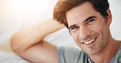 Buy stock photo Portrait of a handsome young man lying in bed and leaning on his hands