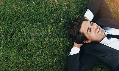 Buy stock photo A young businessman lying down on green grass