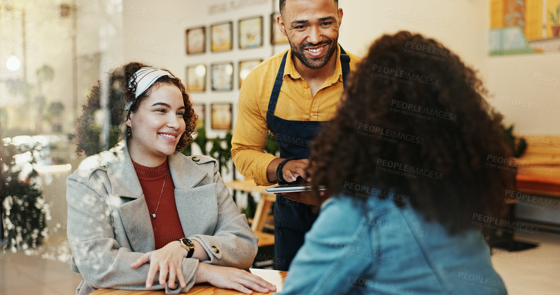 Buy stock photo Coffee shop, women and waiter order with tablet, conversation and customer service at restaurant. Barista, staff and happy girl friends with smile and chat at diner with employee helping with tech