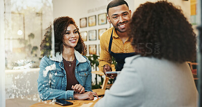 Buy stock photo Coffee shop, friends and waiter order with tablet, conversation and customer service at restaurant. Barista, staff and happy women with smile and chat at diner with employee helping with tech