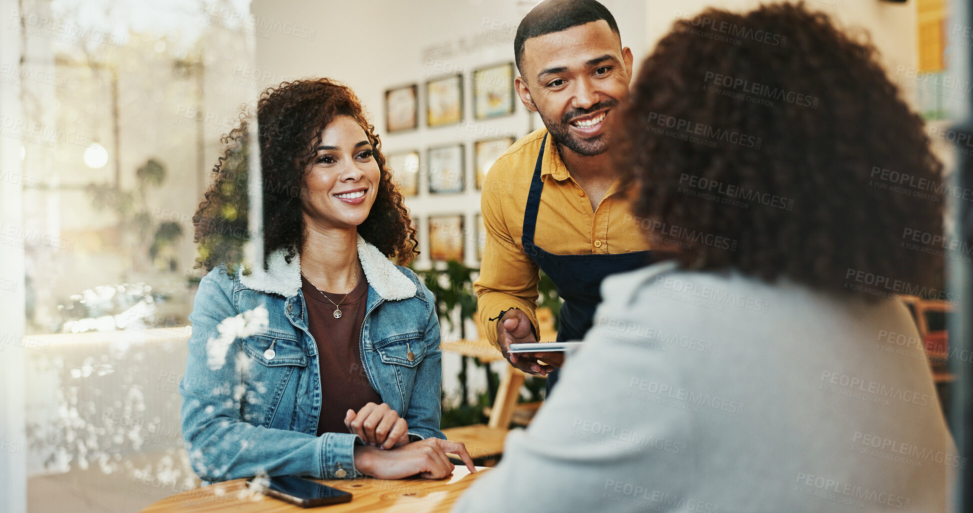 Buy stock photo Coffee shop, friends and waiter order with tablet, conversation and customer service at restaurant. Barista, staff and happy women with smile and chat at diner with employee helping with tech