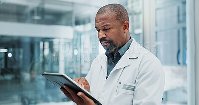 Buy stock photo Black man, doctor and browsing with tablet for medical study, news or telehealth at hospital. African male person or healthcare employee scrolling on technology for online service or app at clinic