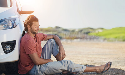 Buy stock photo A young man sitting on the road against the wheel of his car