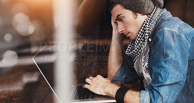 Buy stock photo Shot of a young man sitting at a laptop