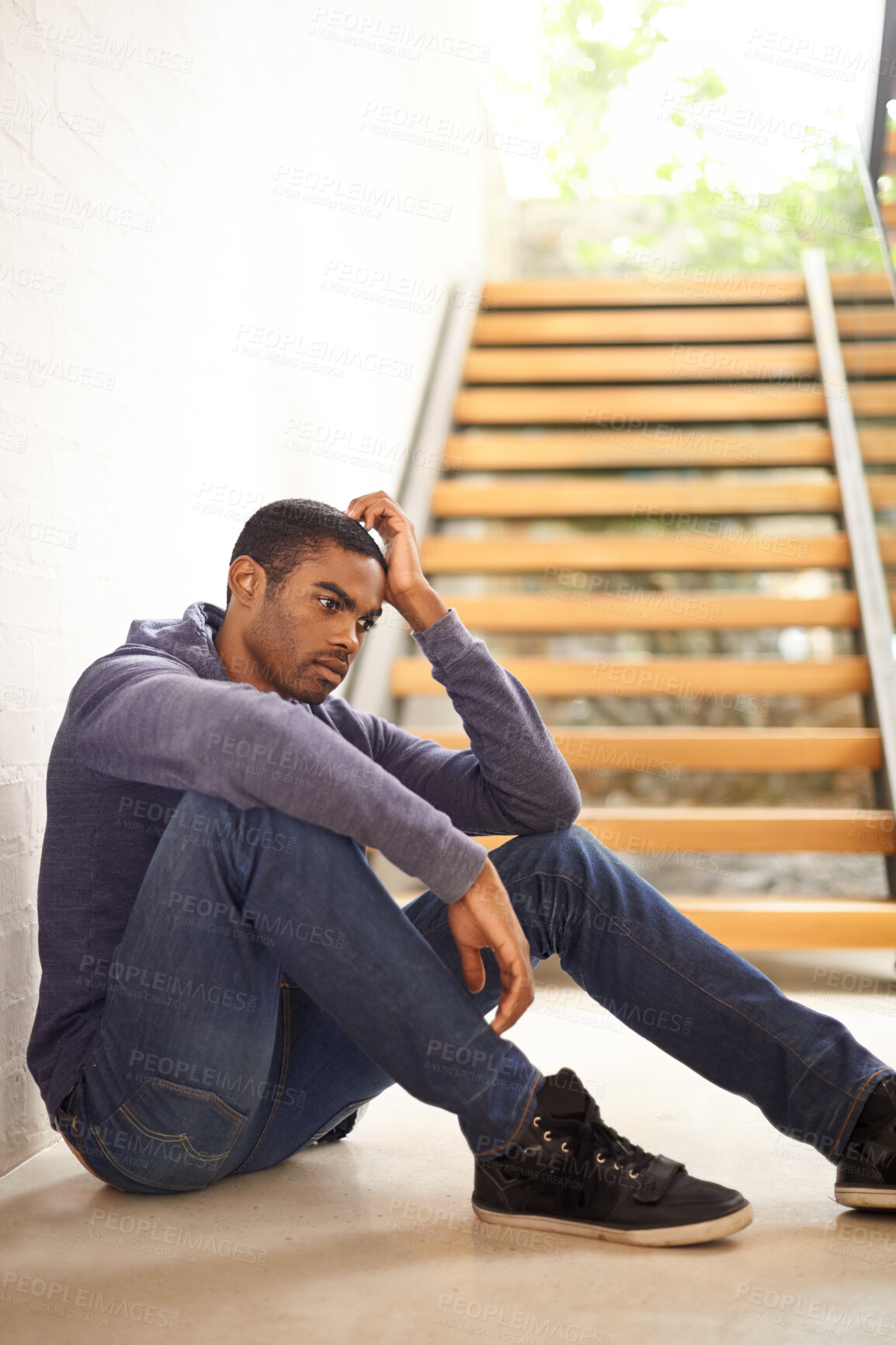 Buy stock photo An unhappy young man sitting on the ground as his girlfriend is packing up to leave