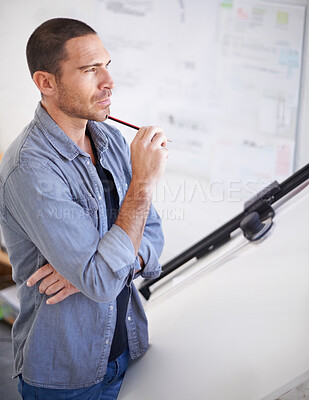 Buy stock photo Cropped shot of an architect looking thoughtful beside his drawing table