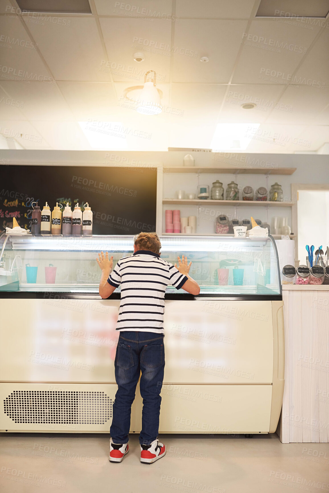 Buy stock photo Rear view shot of a young boy looking into a freezer at an ice cream store