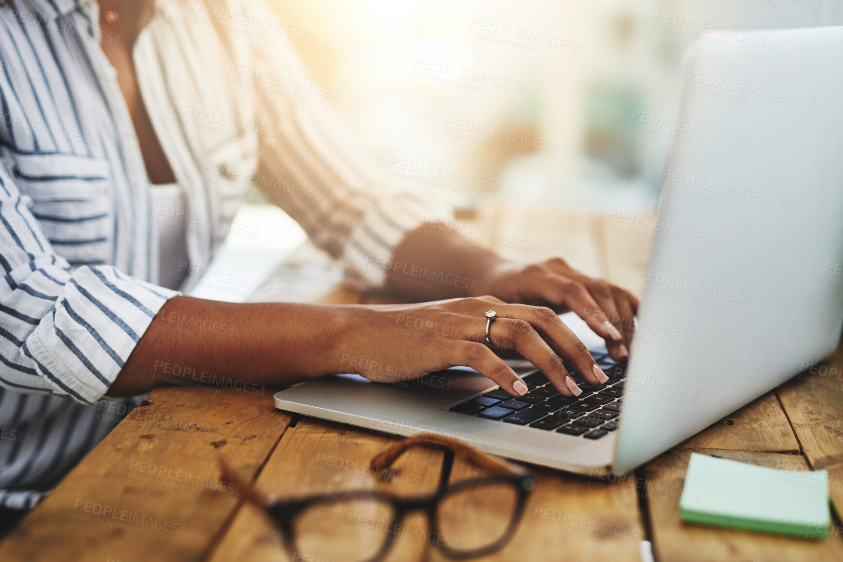 Buy stock photo Cropped shot of a woman using her laptop on a wooden table