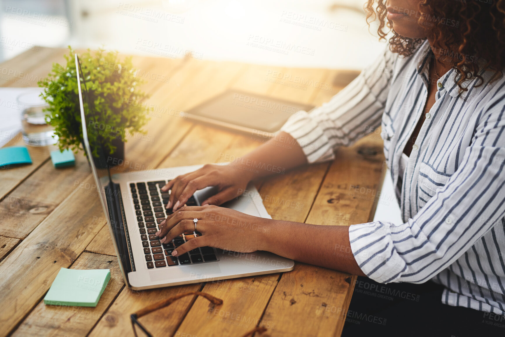 Buy stock photo Cropped shot of a woman using her laptop on a wooden table