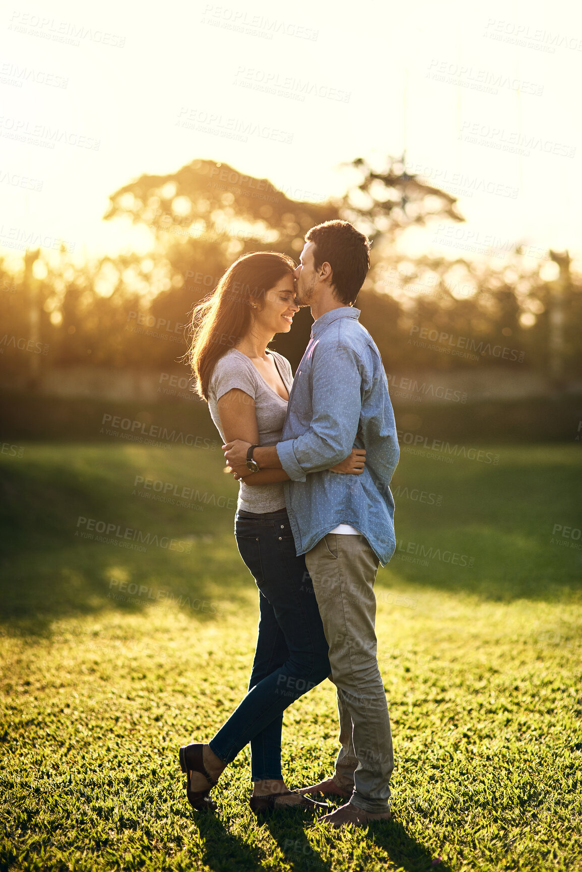 Buy stock photo Kiss, date and happy couple at park for love, care and bonding together outdoor. Romance, man and woman at embrace at garden for commitment, support and connection for healthy relationship on grass