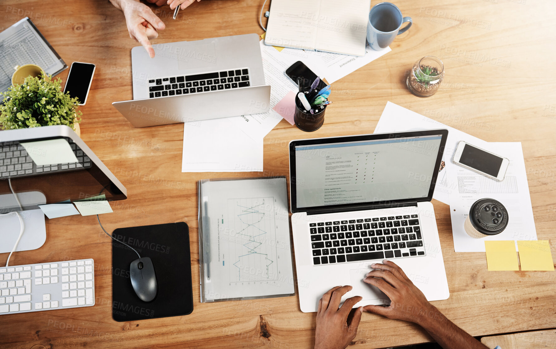 Buy stock photo Above, hands and team in office with laptop, research and strategic planning at desk. People, tech or papers in meeting for statistics, company development or budget control with screen or discussion