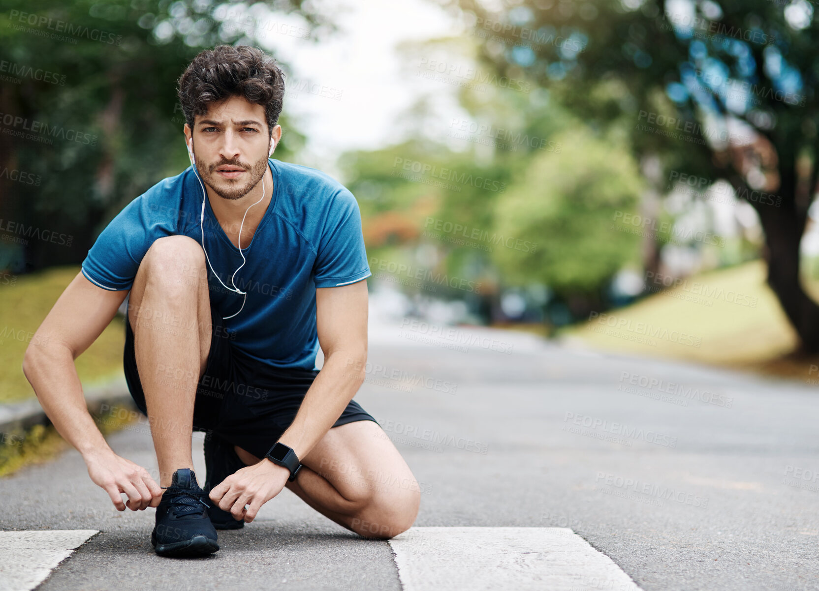 Buy stock photo Shot of a sporty young man tying his shoes before going for a jog outside during the day