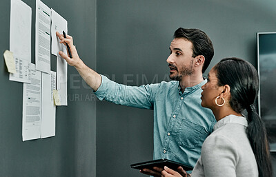 Buy stock photo Shot of two architects working with blueprints on a wall in an office