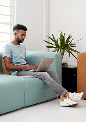 Buy stock photo Computer, remote work and black man typing on sofa for research, project or online report in home. Freelancer, laptop and copywriter writing article, story or reading email on internet in living room